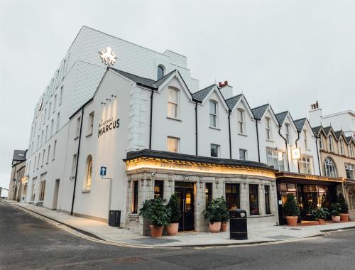 a large white building with potted plants on a street at The Marcus Portrush, Tapestry Collection By Hilton in Portrush