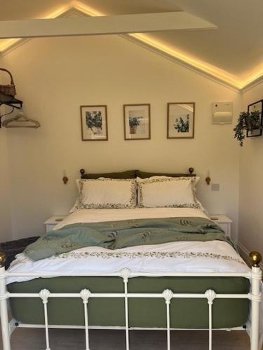 a bedroom with a green bed with four pictures on the wall at The Resting Shepherd in Angmering