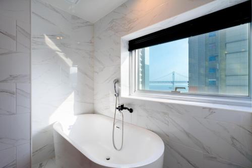 a white bathroom with a sink and a window at Gray 193 Hotel in Busan