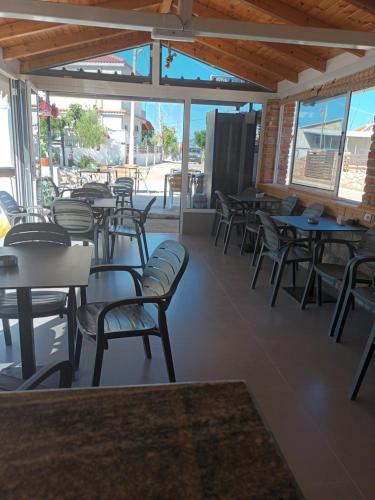 Un restaurante vacío con mesas, sillas y ventanas. en Villa Leonardi, en Ksamil