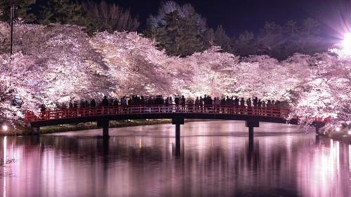 a group of people walking across a bridge over a river at Kanesada Ryokan in Kuroishi
