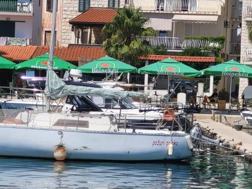 a white boat docked at a dock with green umbrellas at Harbour-side Apartment with Beautiful Terrace in Podgora