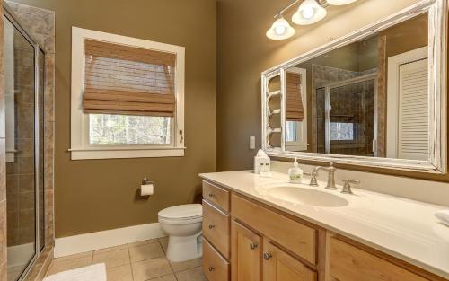 a bathroom with a sink and a toilet and a mirror at Dennys Caribou Lodge -Dog Friendly Stone Fireplace King Suites in Jasper