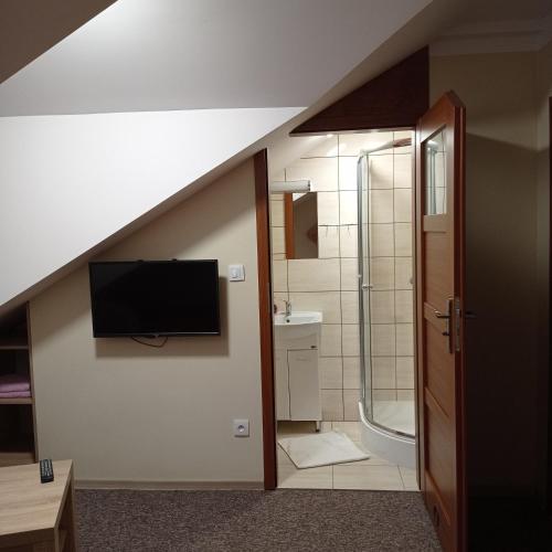 a bathroom with a sink and a tv on the wall at Ośrodek Wczasowy "Wczasy pod gruszą" in Biecz