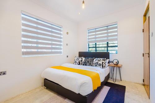 a white bedroom with a bed and two windows at Chique 1BR Villa with Lush Garden Nakuru Town in Nakuru