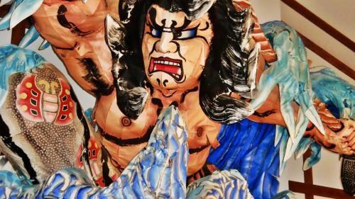 a group of clown masks hanging on a wall at Kanesada Ryokan in Kuroishi