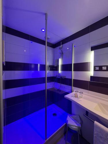 a bathroom with a sink and a shower with blue lighting at The Originals City - Hôtel Saint-Martial, Limoges Centre in Limoges
