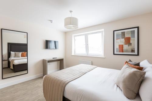 a white bedroom with a bed and a mirror at House of Fisher - Central Gate in Newbury