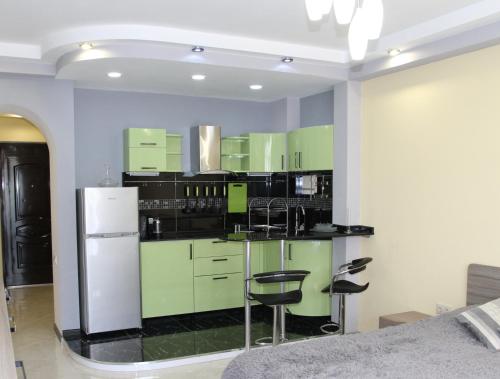 cocina con armarios verdes y nevera blanca en Apartment at Sunset Kvariati, en Kvariati