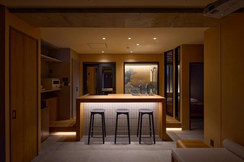 a kitchen with three bar stools at a counter at Tsubomi Shibuya in Tokyo