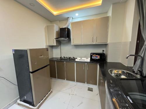 a small kitchen with a refrigerator and a sink at Staycation Apartments in Lahore