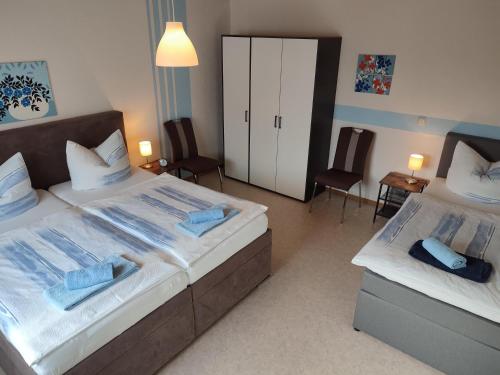 two beds in a bedroom with two chairs and a cabinet at Ferienhaus Gönen in Bleialf