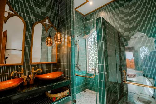 a green tiled bathroom with two sinks and a mirror at La Marrocco Villas in Nusa Penida