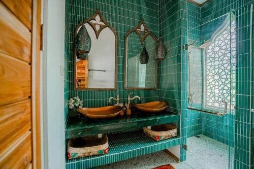 a green bathroom with two sinks and a mirror at La Marrocco Villas in Nusa Penida
