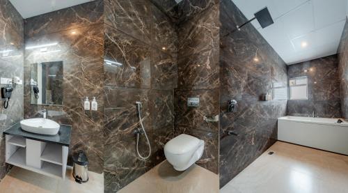 a bathroom with a toilet and a shower and a sink at Pravasa Hotel Vijayapura in Bijāpur