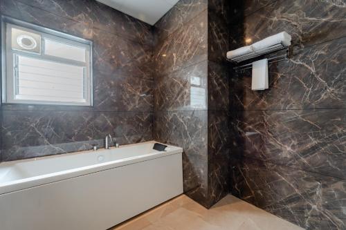 a bathroom with a tub and a sink and a window at Pravasa Hotel Vijayapura in Bijāpur