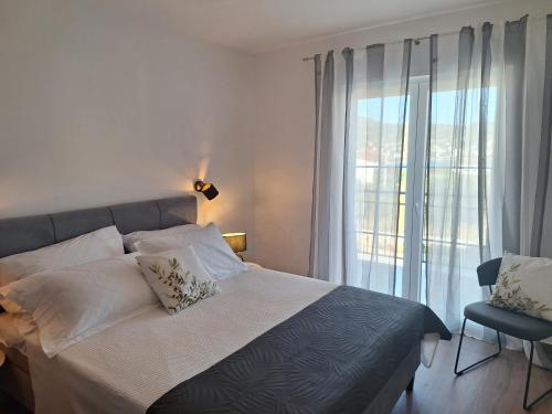 a bedroom with a bed and a large window at Apartmani Jerka in Vinišće