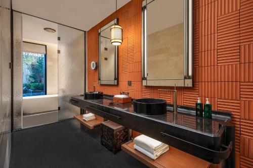 a bathroom with a sink and a mirror and a tub at Hotel Indigo Nalati by IHG in Narat