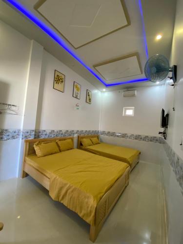 a bedroom with a bed with yellow sheets and blue lights at Nhà nghỉ Bá Thành - Lý Sơn in Quang Ngai