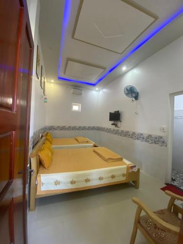 a room with a bed with a blue light on the ceiling at Nhà nghỉ Bá Thành - Lý Sơn in Quang Ngai