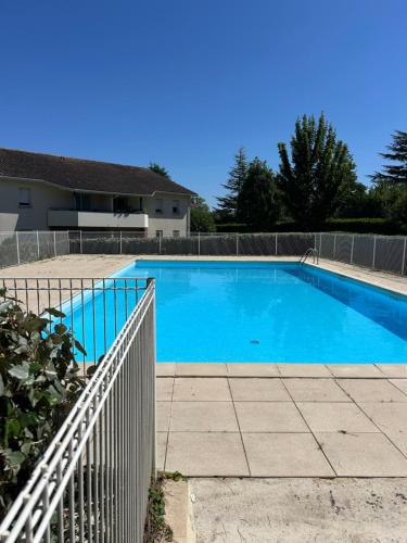une grande piscine bleue à côté d'une clôture dans l'établissement Appartement avec bacon et piscine, à Blaye