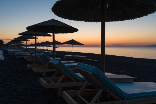 a row of chairs and umbrellas on a beach at Santorini Crystal Blue Boutique Hotel in Kamari