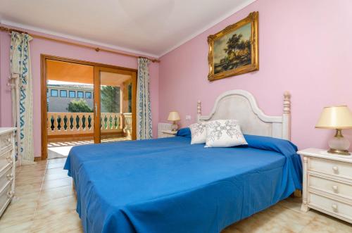 1 dormitorio con cama azul y balcón en Sa Coma (Llampúdol), en Sa Coma