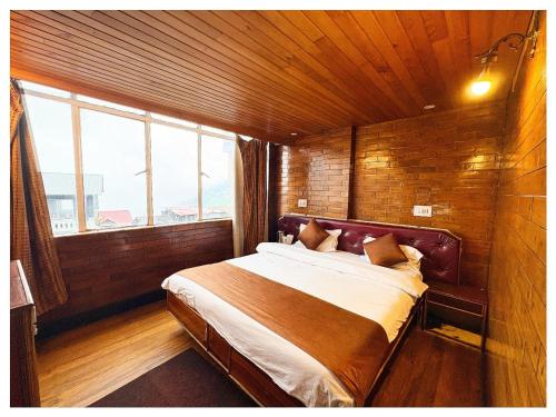 a bed in a room with a large window at Darjeeling Mall is 700 m From Apsara Darjeeling Pure veg in Darjeeling