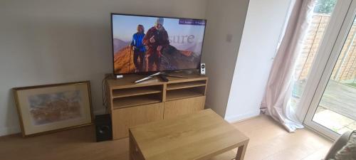Una sala de estar con un televisor de pantalla plana y una mesa. en Diadem Comfort Suites, en Dartford