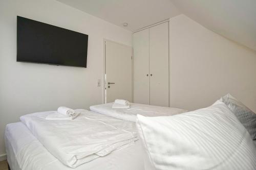 two beds in a room with a tv on the wall at Ferienhaus TimpeTe Haus Backbord - Terrasse, Meerblick, Sauna in Gager