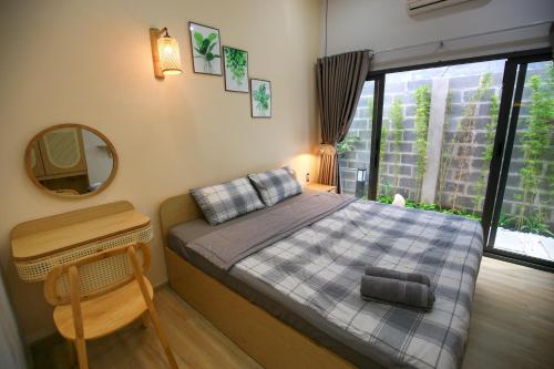 una camera da letto con un letto, uno specchio e una finestra di Trăng Non Homestay a Phan Thiet