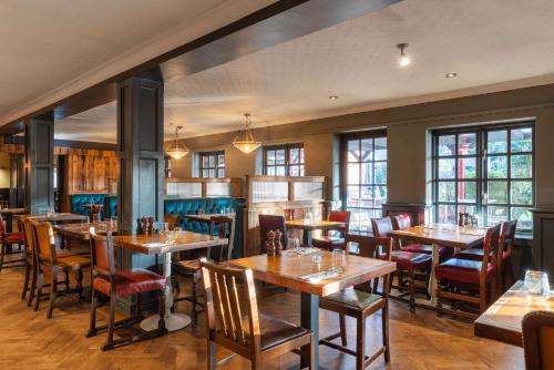 a restaurant with wooden tables and chairs and windows at The Huntsman of Brockenhurst in Brockenhurst
