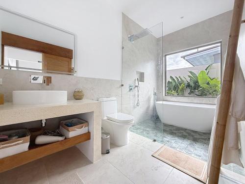a bathroom with a tub and a toilet and a sink at Villa Panad 3BR Balinese Style in Amphoe Koh Samui