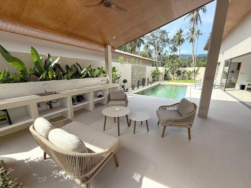 a patio with chairs and a table and a pool at Villa Panad 3BR Balinese Style in Amphoe Koh Samui