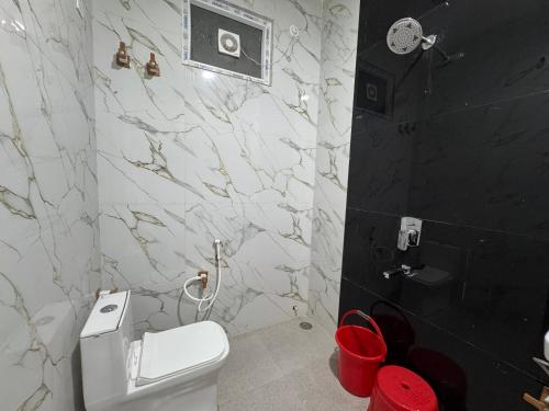 a bathroom with a white toilet and a marble wall at Satya Nikunj INN in Vrindāvan