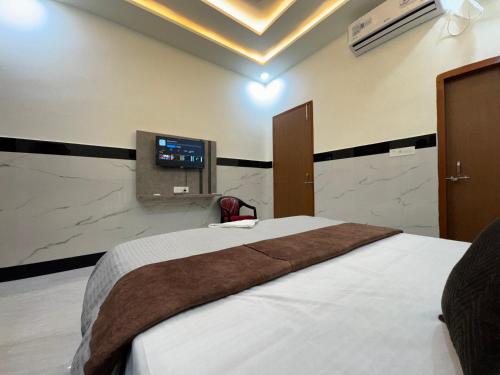 a bedroom with a bed and a tv on the wall at Satya Nikunj INN in Vrindāvan