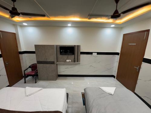 a room with two beds and a tv on a wall at Satya Nikunj INN in Vrindāvan