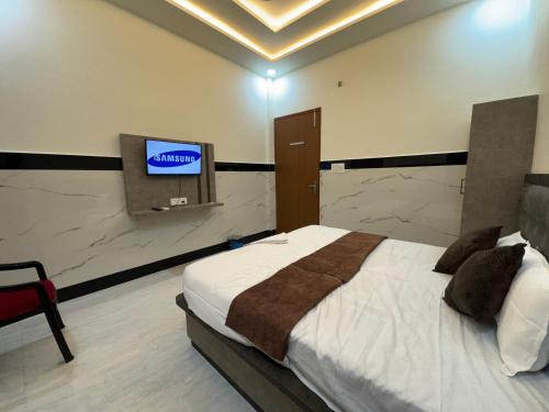 a bedroom with a bed and a tv on a wall at Satya Nikunj INN in Vrindāvan