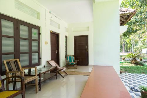 a porch with chairs and a wooden table at Aqualillies Water Front Heritage Homestay in Kumarakom