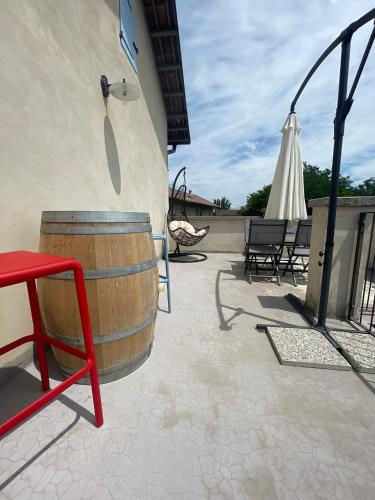 a patio with a barrel and a chair and an umbrella at La casa di Noah in Bene Vagienna
