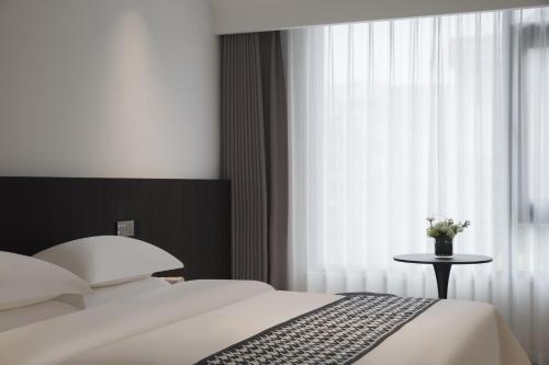 a bedroom with a bed and a window with a table at 西度国际酒店义乌国际商贸城店 in Xialuozhai