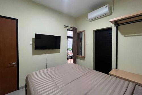 a bedroom with a bed and a flat screen tv at Rooms at Deceva by Panorama Villas, Batu Malang in Batu