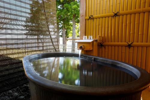 a bath tub sitting next to a yellow wall with a fountain at 純和風旅亭 碧翠御苑 in Kyotango