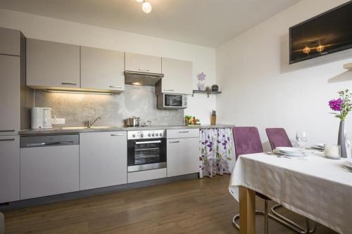 a kitchen with white cabinets and a table and a dining room at Haus Angela in Rohrberg