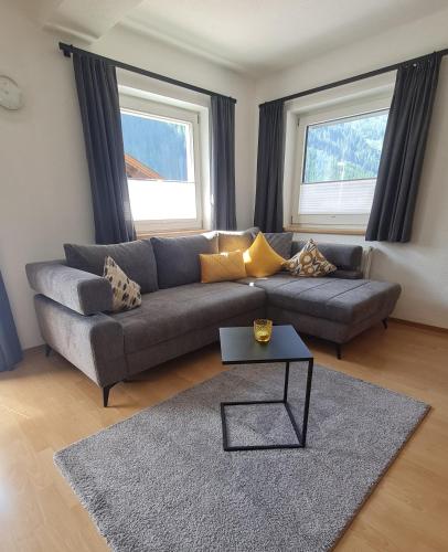 a living room with a gray couch and two windows at Haus Alpenheim Apartment 3 in Tux