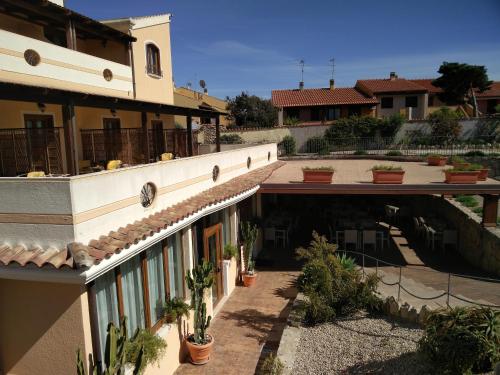a building with a courtyard with potted plants at Hotel Raffael PHG in Putzu Idu