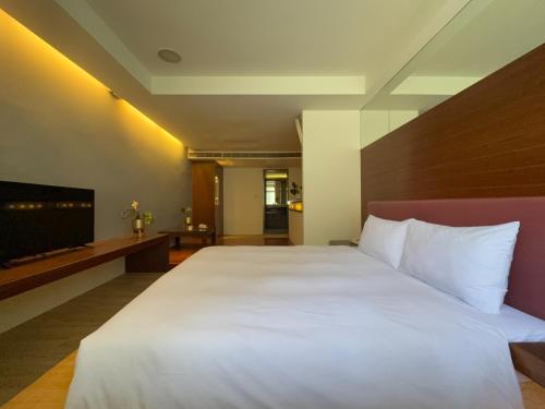 a bedroom with a large bed and a flat screen tv at 喃行旅-一房一車位 毛孩友善客房數量有限請先預約 in Tainan