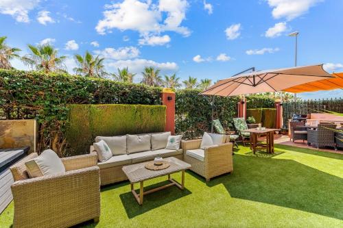 patio con divano, ombrellone ed erba di Royal Park Spa a Campoamor
