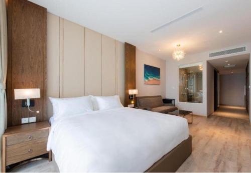 a bedroom with a large white bed and a living room at Panorama Nha Trang Sunlight Apartment in Nha Trang