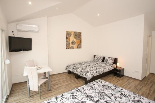 a bedroom with two beds and a desk and a tv at Apartments & Rooms Villa Zaad FREE PRIVATE PARKING in Mostar